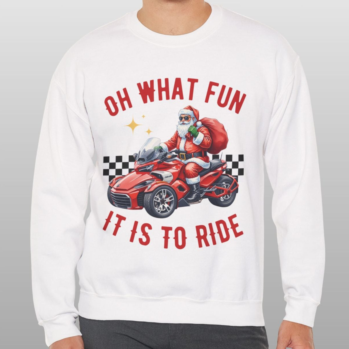 Person wearing a white sweatshirt with a graphic of Santa driving a car and text 'Oh what fun it is to ride' on a gray background.