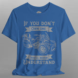 Blue t-shirt with graphic of a three-wheeled vehicle and text on a gray background