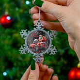 Person holding a snowflake-shaped Christmas ornament with Santa Claus and reindeer in front of a decorated tree.