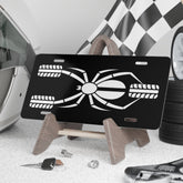 Black license plate with white design on a stand, surrounded by car parts and tools.