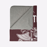 Folded gray and maroon towel with a design on a light beige background