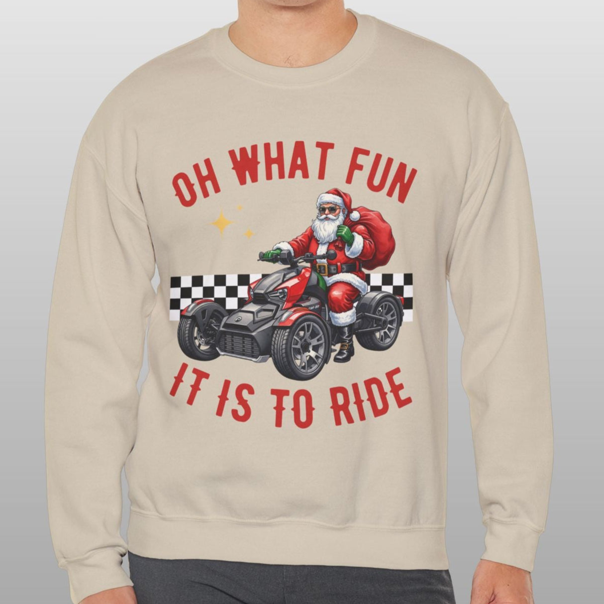 Man wearing a beige sweatshirt with a graphic of Santa Claus on a motorcycle and text 'OH WHAT FUN IT IS TO RIDE' on a plain background.