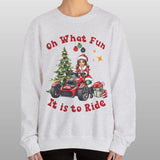 Person wearing a Christmas-themed sweatshirt with a design of a child in a Santa hat driving a red vehicle near a Christmas tree, with text 'Oh What Fun It is to Ride'.