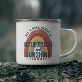 White mug with 'All a girl needs is motorcycles and sunshine' text on a wooden surface with a blurred natural background