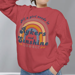 Person wearing a red sweatshirt with a colorful graphic and text, standing against a plain background.