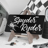 Personalized license plate with 'Spyder Ryder' on a stand, surrounded by automotive items.