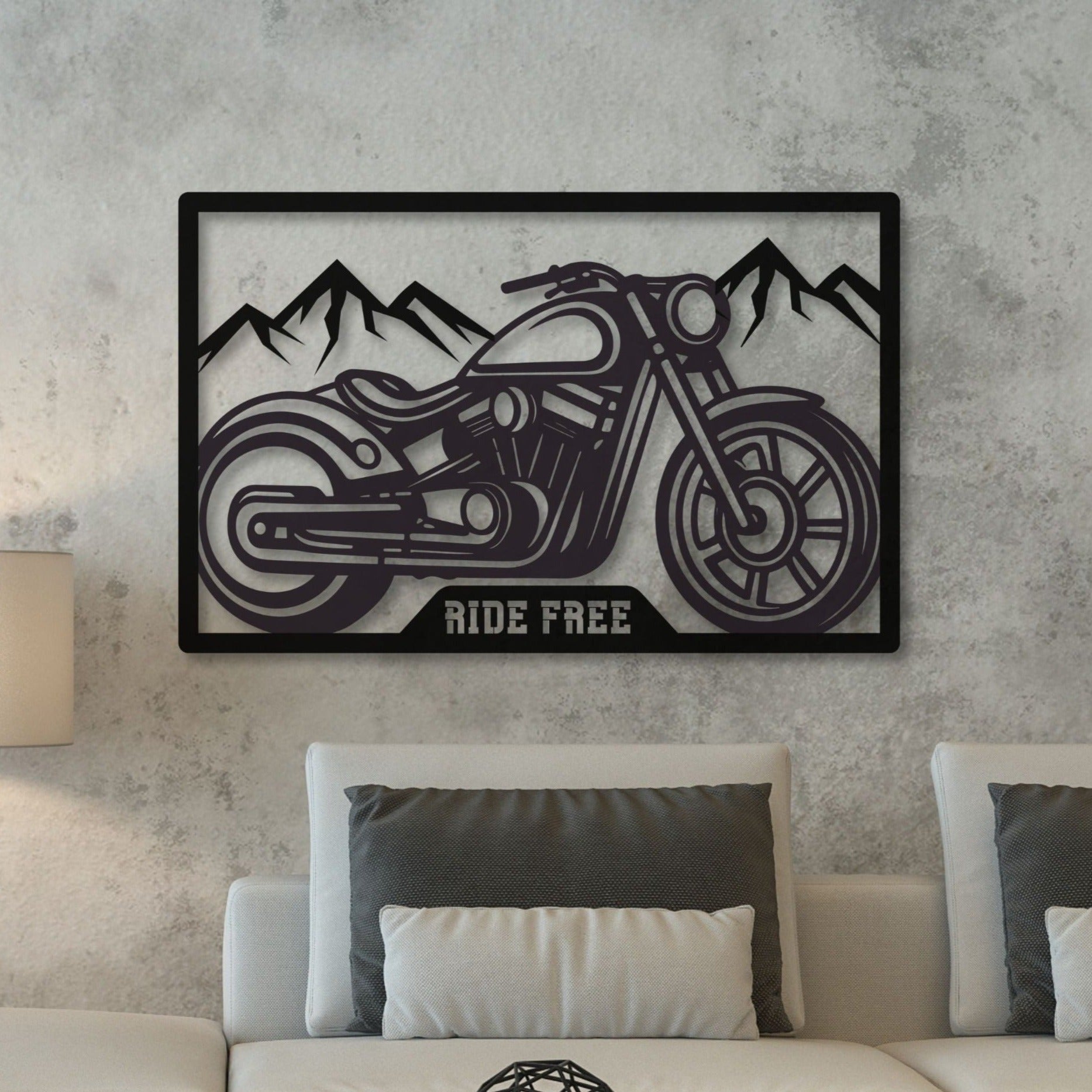 A metal wall art depicting a motorcycle with 'RIDE FREE' text, mounted on a grey wall above a white sofa with grey pillows.