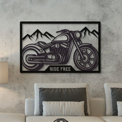 A metal wall art depicting a motorcycle with 'RIDE FREE' text, mounted on a grey wall above a white sofa with grey pillows.