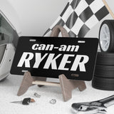 Can-Am Ryker license plate on a stand with a helmet, checkered flag, and tires in the background.