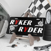 License plate with 'RYKER RYDER' text and skull design on a stand with car accessories in the background.