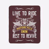 Blanket with motorcycle design and text 'Live to Ride, Motorcycle Inn, Rest to Revive' on a green wall.