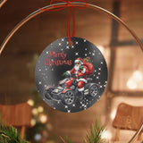 Decorative Christmas ornament with Santa Claus on a motorcycle, placed on a wooden slice with greenery and red ornaments.