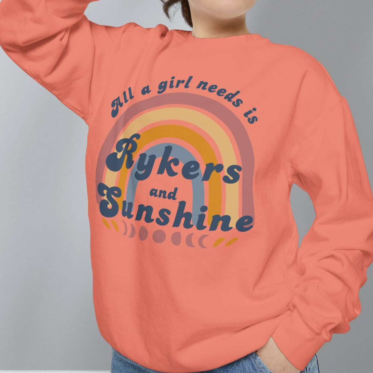 Person wearing a coral sweatshirt with text and rainbow design on a gray background