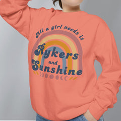 Person wearing a coral sweatshirt with text and rainbow design on a gray background