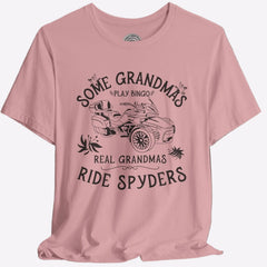 A pink crew neck t-shirt with a graphic print that reads 'Some Grandmas play bingo. Real Grandmas ride Spyders' and depicts a motorcycle.