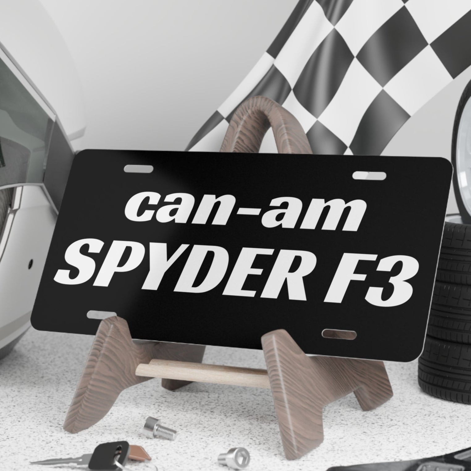 Black license plate with 'can-am SPYDER F3' text on a stand, surrounded by automotive items.