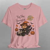 Pink t-shirt with Halloween-themed design featuring a cartoon witch and pumpkins on a gray background.