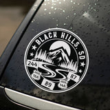 Car window with a 'Black Hills, SD' decal featuring mountain and road design.