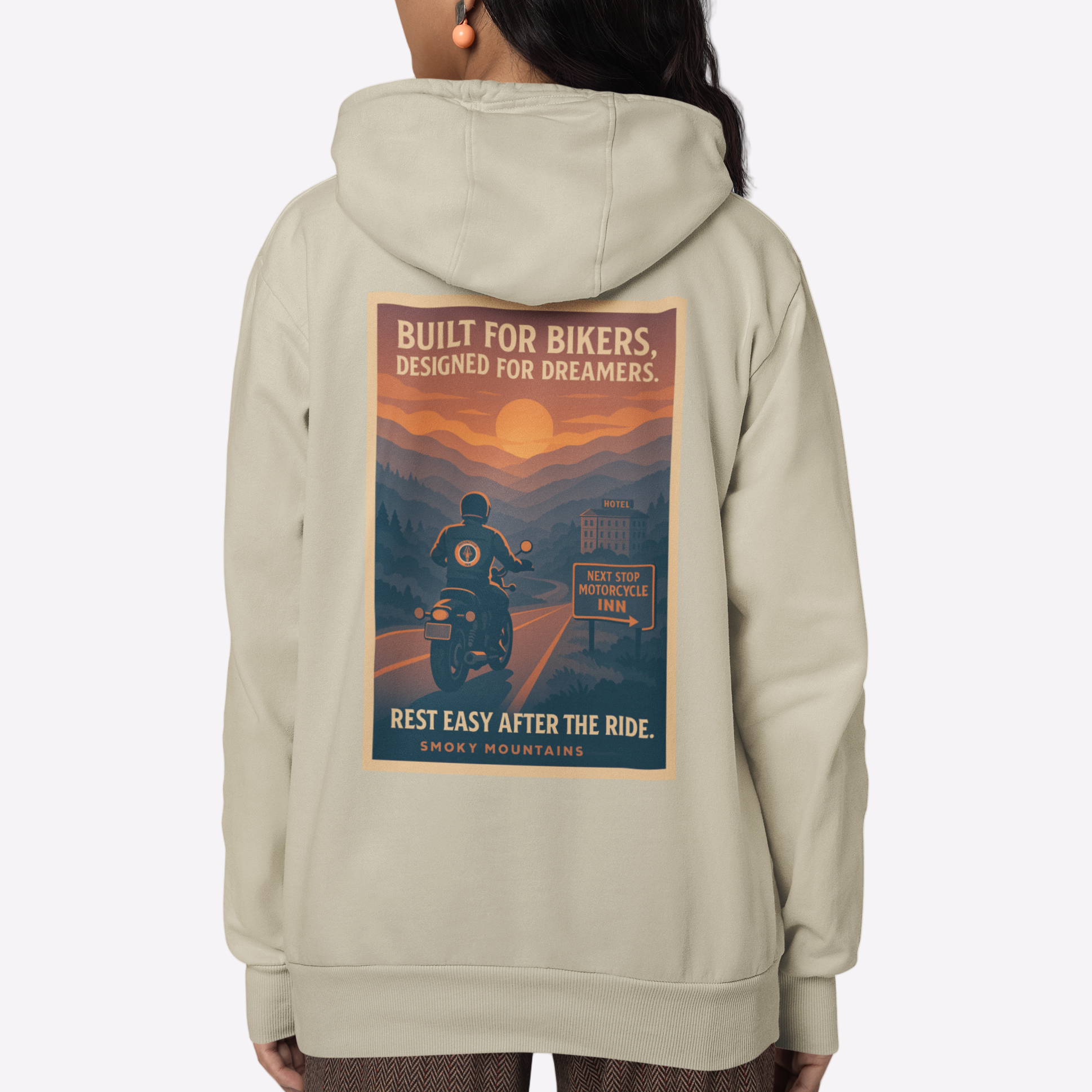 Person wearing a beige hoodie with a graphic design on the back, standing against a white background