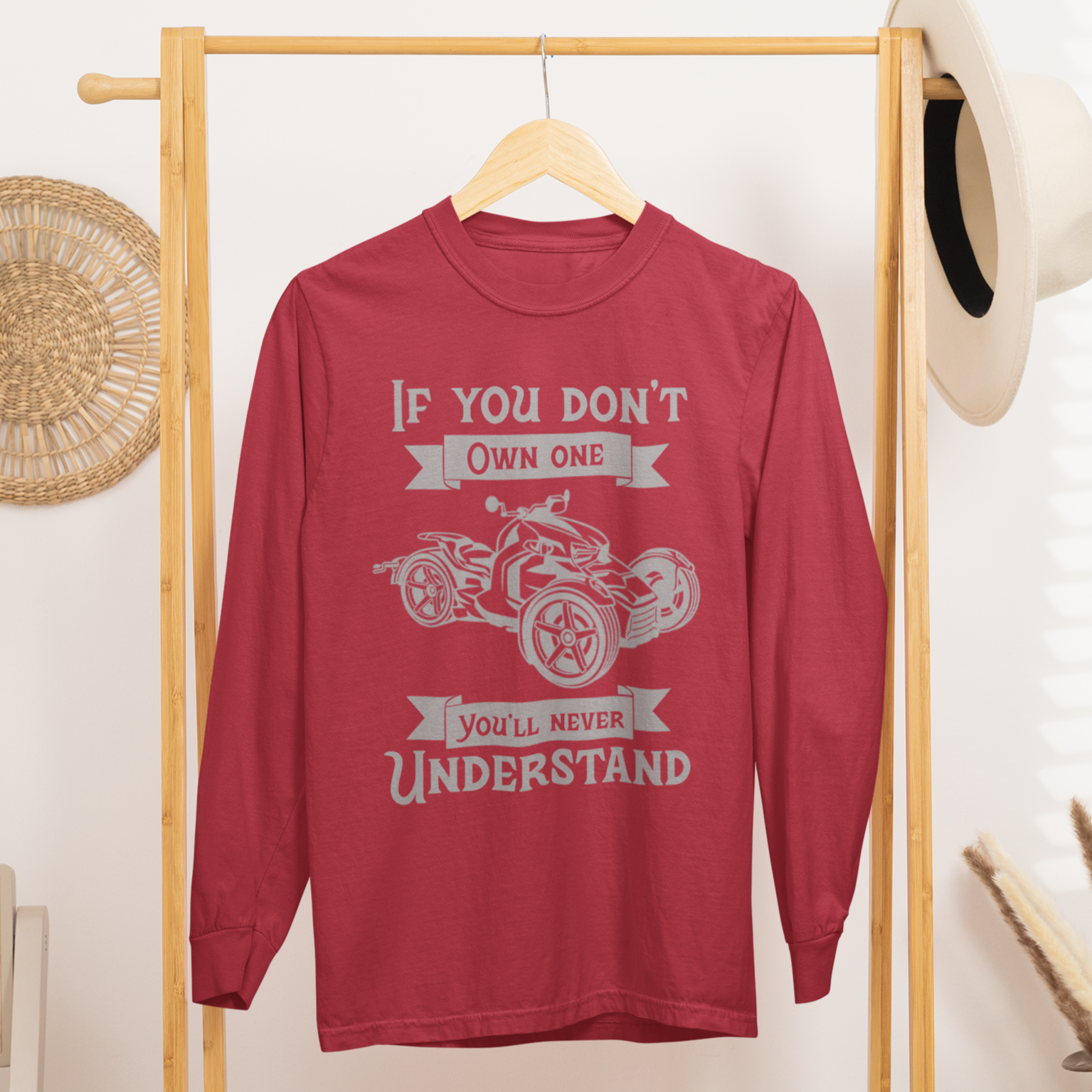 Red sweatshirt with graphic design on a wooden rack in a room setting.