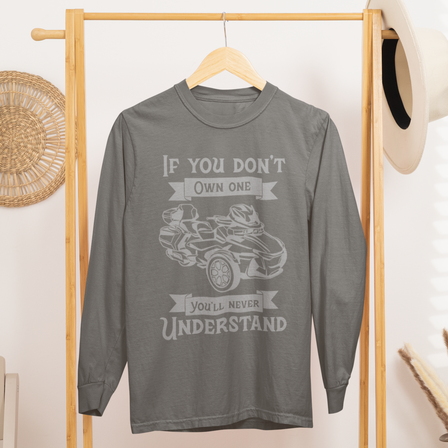 Gray long-sleeve shirt with graphic design on a wooden rack in a room setting.