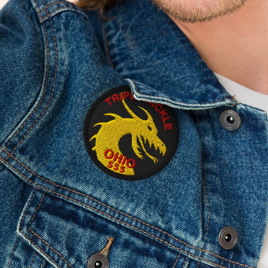 Man wearing a denim jacket with a dragon patch on a beige background