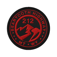 A circular embroidered patch featuring the text 'BEARTOOTH HIGHWAY' and 'MT WY' in red around a mountain and lightning bolt design, with '212' in the center, on a black background.
