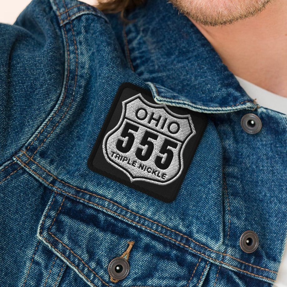 Man wearing a denim jacket with a patch on a beige background