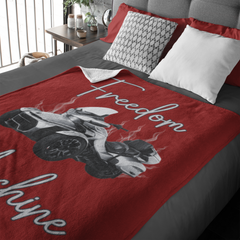 Red blanket with a graphic design and text on a bed in a bedroom setting.