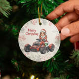 Hand holding a Christmas ornament with a child in a Santa hat and car design, surrounded by festive decorations.