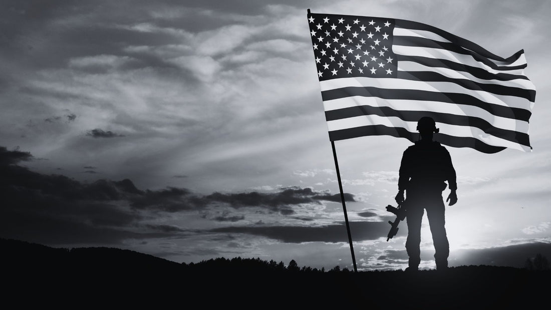 Soldier standing by US Flag with sunset in background