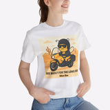 Person wearing a white t-shirt with a graphic design of a bee on a motorcycle, sitting in a room with a plant.