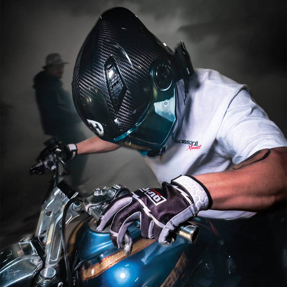 Person wearing a helmet and gloves on a motorcycle with a dark background