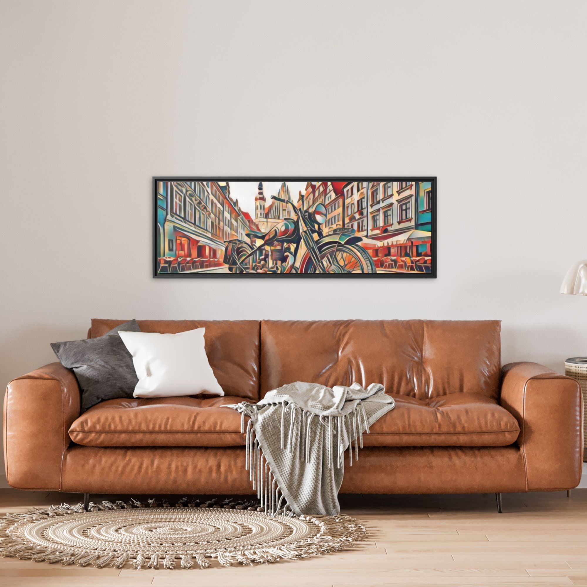 Brown leather sofa with decorative pillows and a blanket in a living room setting, featuring a colorful framed painting on the wall.