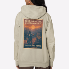 Person wearing a beige hoodie with a graphic design on the back, standing against a white background