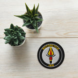 Motorcycle Inn patch on a wooden surface with two small potted succulents.