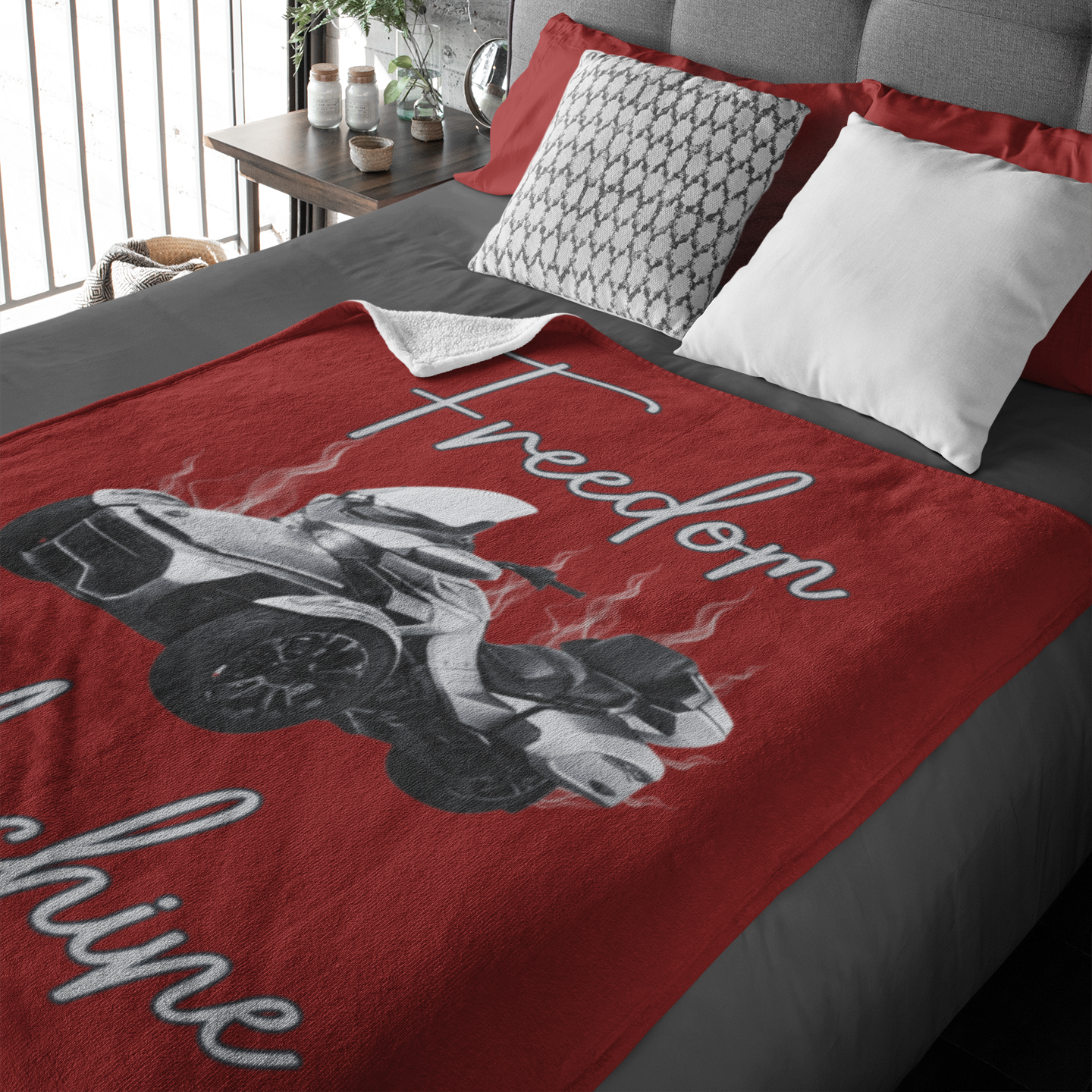 Red blanket with a graphic design and text on a bed in a bedroom setting.